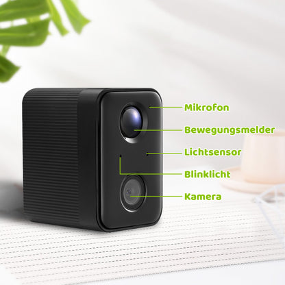 Schwarze kompakte Überwachungskamera mit zwei Linsen und grünen Beschriftungen, die Mikrofon, Bewegungsmelder, Lichtsensor, Blinklicht und Kamera markieren